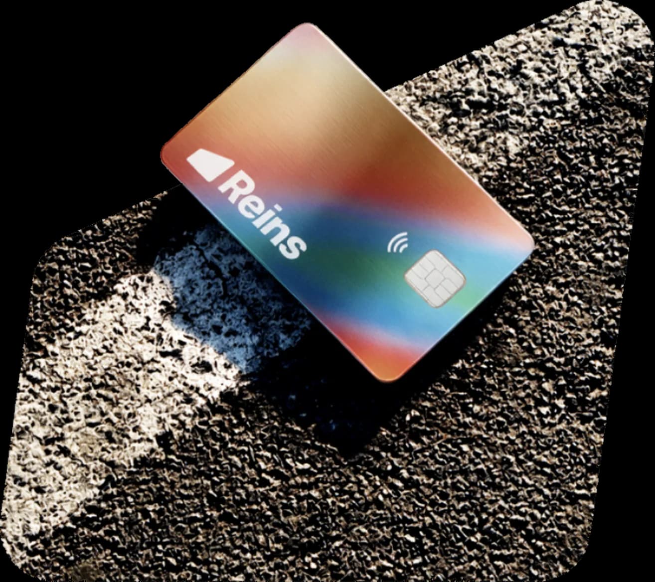 A Reins payment card resting on gravel