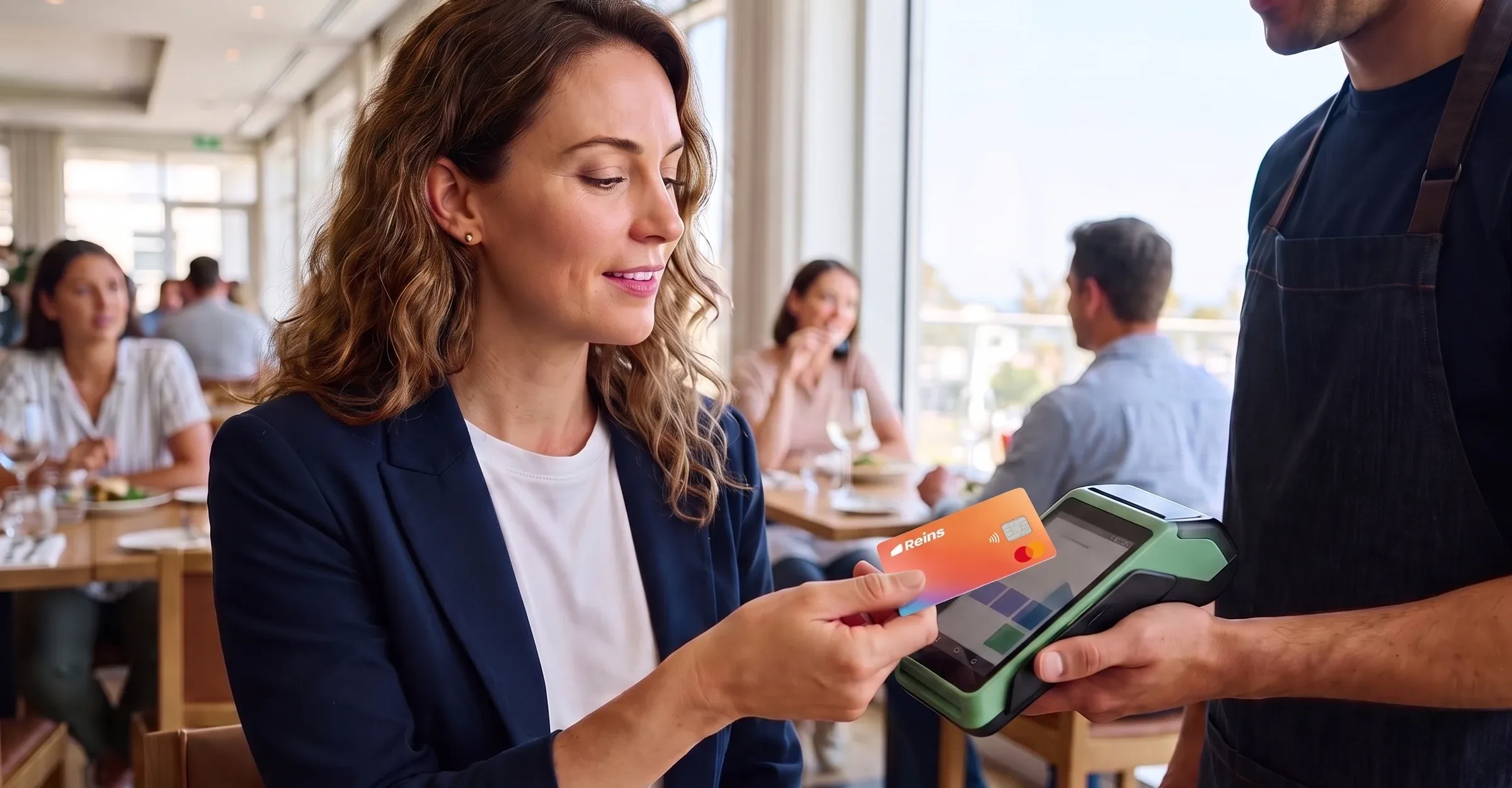 An employee paying a restaurant bill with a Reins card at a handheld terminal
