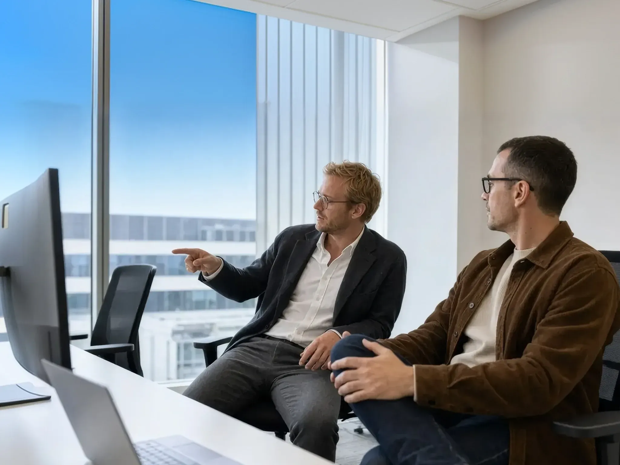 Two men look at a computer screen in an office