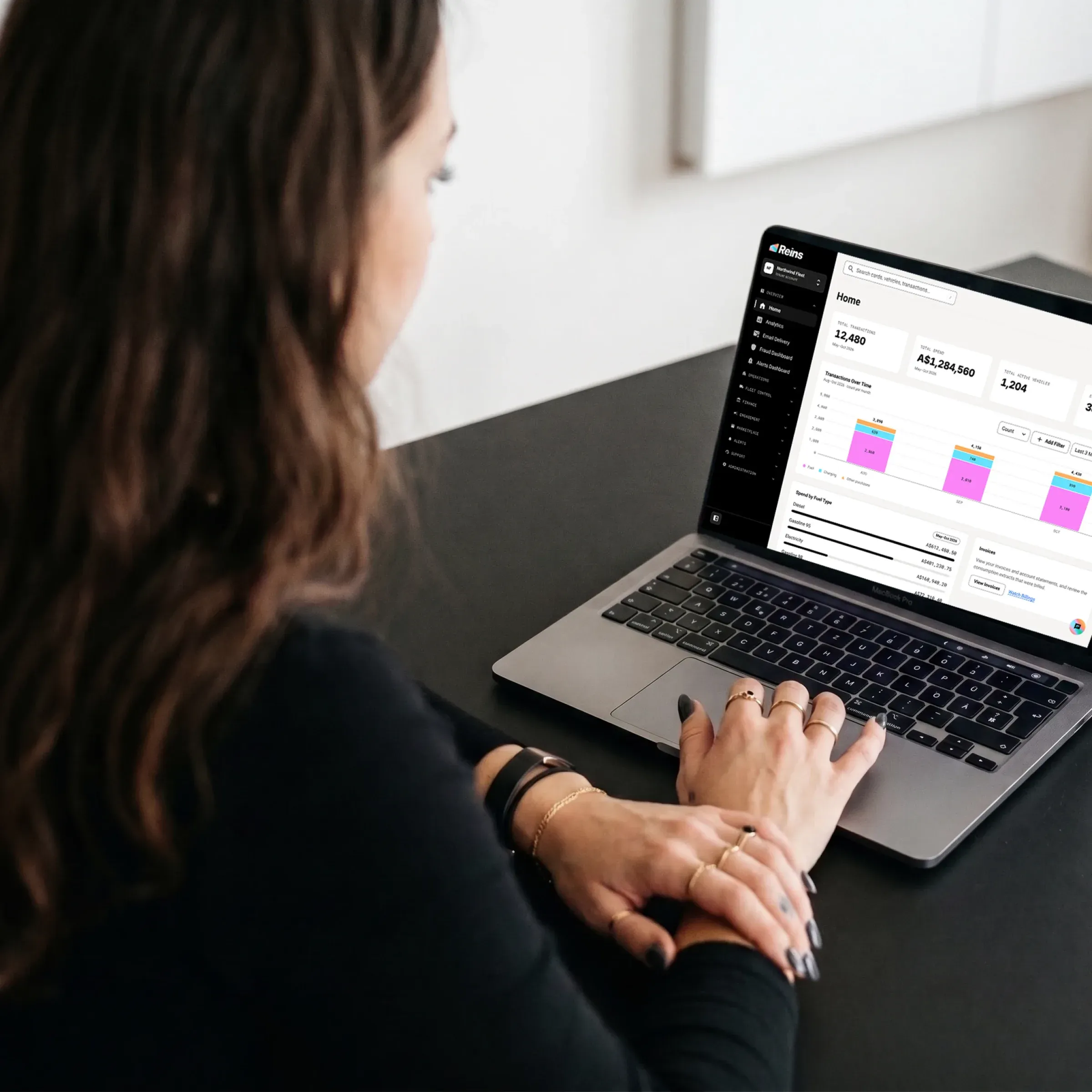 A woman works on a laptop with a dashboard of spend rules